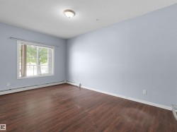 Spacious room featuring wood-finish flooring, light blue walls, and a large window - 