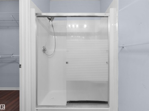 Enclosed shower with a handheld showerhead and sliding frosted glass doors - 106 263 Macewan Road, Edmonton, AB 