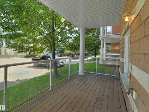 Covered exterior porch featuring wood-finish decking and glass panel railing - 106 263 Macewan Road, Edmonton, AB 