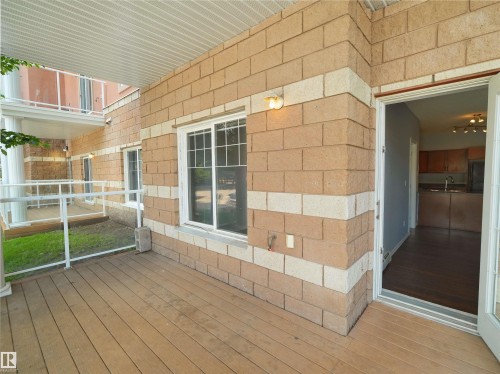 Private outdoor patio featuring wood-finish flooring, a light-colored soffit, and a glass and white railing system - 106 263 Macewan Road, Edmonton, AB 