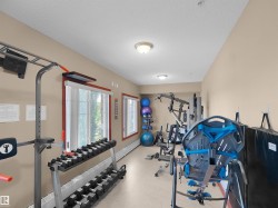 Dedicated fitness area featuring neutral-toned walls, recessed lighting, and multiple windows with red-trimmed frames - 