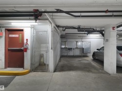 Underground parking area featuring concrete flooring, exposed overhead piping, and fluorescent lighting - 