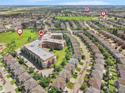Expansive aerial view showcasing a residential neighborhood with a large condominium building, numerous detached homes, a substantial green space, and visible roadways - 