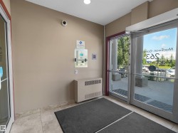Entryway featuring glass double doors, tile flooring, and a wall-mounted intercom system - 