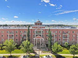 Multi-story residential building featuring a prominent front entrance with columns, a portico, and a central domed architectural element - 
