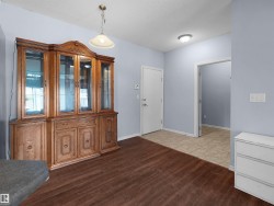 Spacious room featuring wood-finish flooring, light blue wall paint, a white door, and a white ceiling with a flush-mount light fixture - 