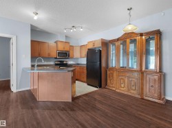 Kitchen featuring wood-finish cabinetry, stainless steel appliances, a center island with a sink, and dark wood-finish flooring - 