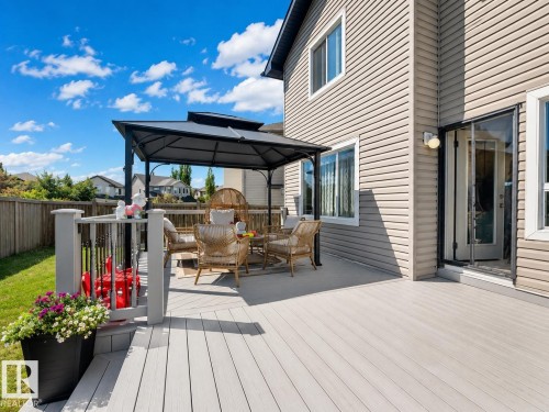 Multi-level outdoor deck featuring a composite wood-finish surface, a black metal gazebo, and a glass-paneled door - 526 173A Street, Edmonton, AB 