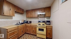 Kitchen featuring ample wood-finish cabinetry, a L-shaped countertop, patterned floor tile, and a built-in range hood - 
