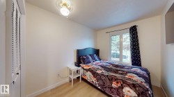 Bedroom featuring light wood-finish flooring, a double-paned window, and a louvered closet door - 
