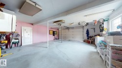 Spacious garage featuring a concrete floor, overhead lighting, an overhead door, and a utility sink - 