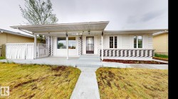 Contemporary ranch-style exterior featuring a covered front porch, decorative patterned fencing, and a concrete walkway - 
