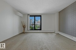 Carpeted interior space featuring a full-height glass door with an integrated balcony, a cityscape backdrop, a ductless mini-split air conditioning unit, patterned accent wall, and baseboard heating - 