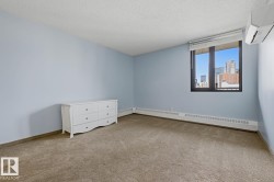 Carpeted room featuring a window with city buildings visible, a wall-mounted mini-split HVAC unit, and baseboard heating - 