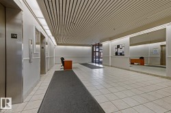 Spacious corridor featuring white tiled flooring, a slatted ceiling, and recessed lighting - 
