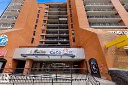 Multi-story brick building facade with multiple balconies and a ground-level commercial entrance - 
