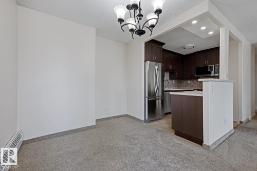 Dining area featuring a contemporary chandelier and wall-to-wall carpeting - 505 10145 109 Street, Edmonton, AB 