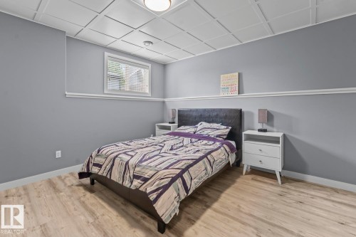 Bedroom featuring wood-finish flooring, a drop ceiling, window with blinds, and light gray painted walls with white trim - 35 Falcon Road, Cold Lake, AB 