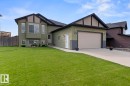 Green siding exterior with black trim accents and a contrasting light-colored garage door - 35 Falcon Road, Cold Lake, AB 