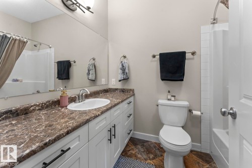 Full bathroom featuring a white vanity with dark hardware, a brown-toned countertop, and an undermount sink with a chrome faucet - 35 Falcon Road, Cold Lake, AB 