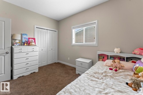 Neutral-toned room featuring a window with horizontal blinds, carpeted flooring, and a white bi-fold closet - 35 Falcon Road, Cold Lake, AB 