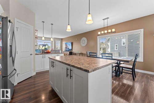 Kitchen featuring a central island with a stone-finish countertop, white cabinetry, dark hardware, and wood-finish flooring - 35 Falcon Road, Cold Lake, AB 