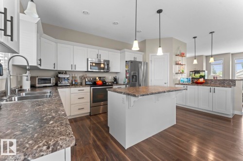 Kitchen featuring a central island with countertop, white cabinetry, dark wood-finish flooring, stainless steel appliances, and recessed lighting - 35 Falcon Road, Cold Lake, AB 