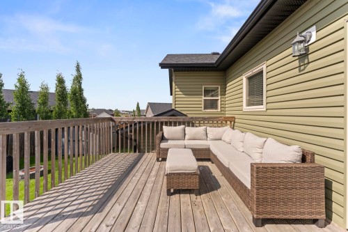 Spacious wood deck with railing, featuring light green horizontal siding and a dark roofline, with a single exterior light fixture - 35 Falcon Road, Cold Lake, AB 