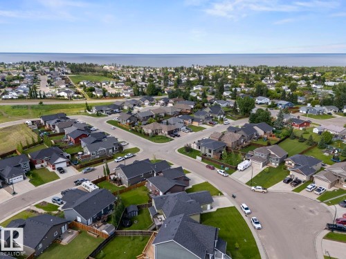 Aerial perspective of a residential neighborhood featuring single-family homes with dark-shingle roofs and green landscaping - 35 Falcon Road, Cold Lake, AB 