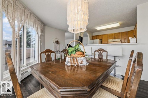 Dining area featuring dark wood-finish flooring, a contemporary chandelier, and direct access to an outdoor space through a large glass door - 427 15499 Castle Downs Road, Edmonton, AB 