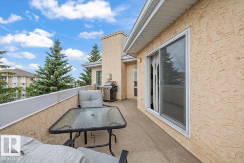 Concrete balcony featuring stucco exterior, white railing, and a large sliding glass door - 427 15499 Castle Downs Road, Edmonton, AB 