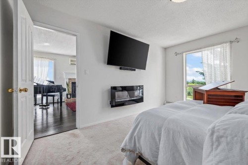 Carpeted bedroom featuring a wall-mounted television and an inset linear electric fireplace - 427 15499 Castle Downs Road, Edmonton, AB 