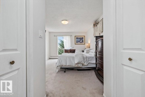 Carpeted room featuring a double window, baseboard heating, and a flush mount ceiling light fixture - 427 15499 Castle Downs Road, Edmonton, AB 