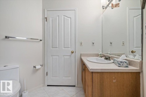 Bathroom featuring a light wood-finish vanity with an integrated sink, a light-toned countertop, and a large wall-mounted mirror - 427 15499 Castle Downs Road, Edmonton, AB 