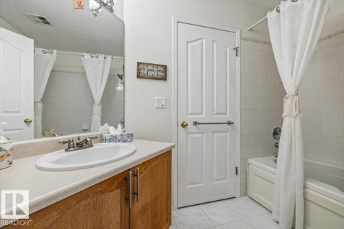Bathroom vanity with an integrated oval sink, light-toned countertop, and wood-finish cabinetry - 427 15499 Castle Downs Road, Edmonton, AB 