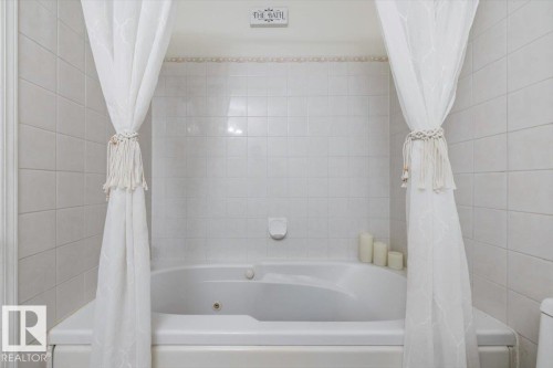 White tiled bathroom featuring a built-in jetted tub - 427 15499 Castle Downs Road, Edmonton, AB 