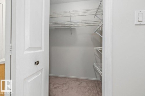 Spacious closet featuring wire shelving, wall-to-wall carpeting, and a panel door with decorative hardware - 427 15499 Castle Downs Road, Edmonton, AB 