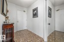 Entryway featuring composite flooring, a white entry door with brass-tone hardware, and a mirrored closet door - 427 15499 Castle Downs Road, Edmonton, AB 