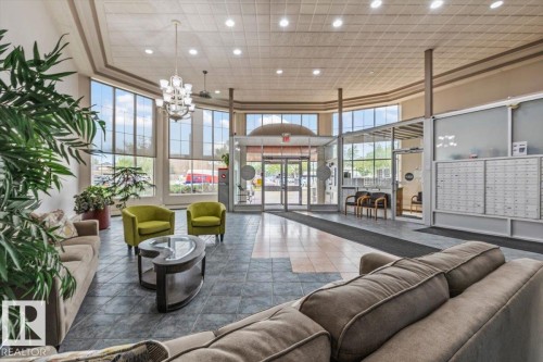 Spacious communal lobby featuring large pane windows, a tiled floor, recessed lighting, and a prominent central chandelier - 427 15499 Castle Downs Road, Edmonton, AB 