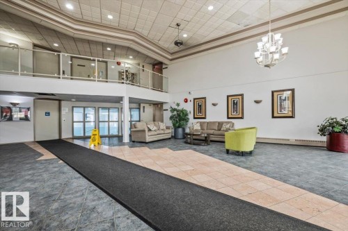 Spacious lobby featuring a high ceiling, chandelier lighting, and a second-story balcony with glass railings - 427 15499 Castle Downs Road, Edmonton, AB 