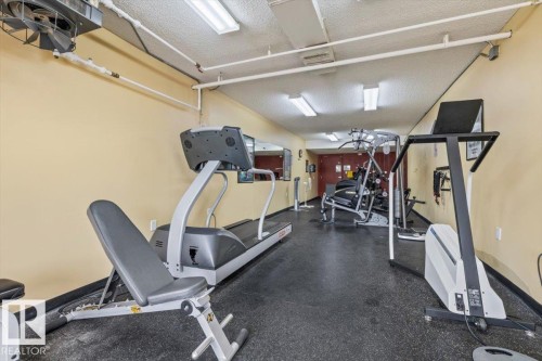 Fitness center featuring multiple exercise machines, cushioned flooring, and perimeter mirrors - 427 15499 Castle Downs Road, Edmonton, AB 