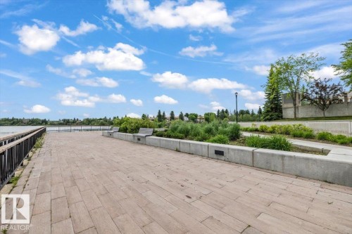 Expansive paved walkway featuring a metal railing, built-in benches, integrated lighting, and surrounding landscaping - 427 15499 Castle Downs Road, Edmonton, AB 