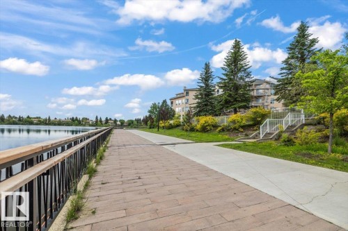 Waterfront promenade featuring a decorative railing, paver pathway, and concrete walkway - 427 15499 Castle Downs Road, Edmonton, AB 