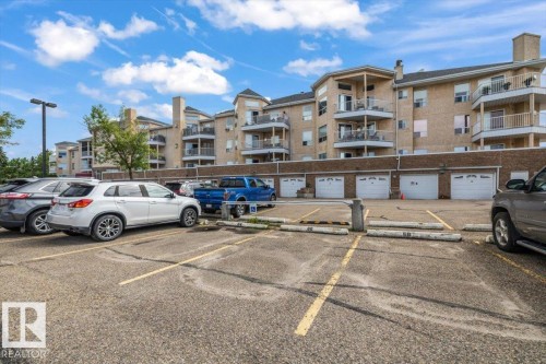 Multi-story building featuring brick and stucco exterior, multiple private balconies, and individual garage doors - 427 15499 Castle Downs Road, Edmonton, AB 