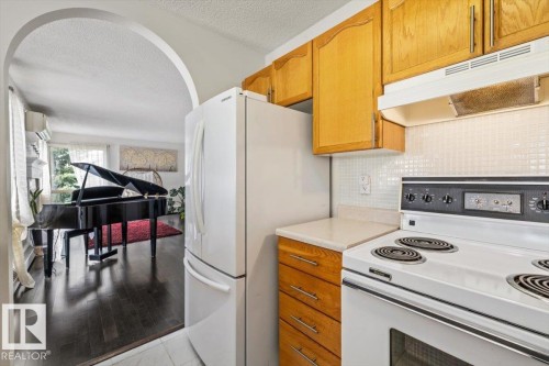 Kitchen area featuring wood cabinetry, white appliances, and a tiled backsplash - 427 15499 Castle Downs Road, Edmonton, AB 