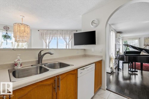 Kitchen counter with a double stainless steel sink, a gray faucet, and light-toned countertops - #427 15499 Castle Downs Rd Nw, Edmonton, AB - Indoor Photo Showing Kitchen With Double Sink
