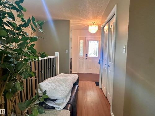 Entryway featuring wood-finish flooring, a decorative glass front door with sidelights, and a contemporary ceiling light fixture - 10619 108 Avenue, Westlock, AB - Indoor