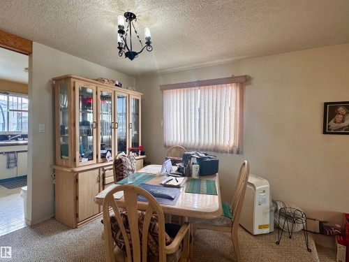 Dining area featuring textured ceiling, a decorative chandelier, and carpeting - 10619 108 Avenue, Westlock, AB - Indoor Photo Showing Dining Room