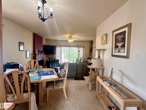 Living area featuring a brick accent wall, ceiling fan, and carpeted flooring - 10619 108 Avenue, Westlock, AB - Indoor