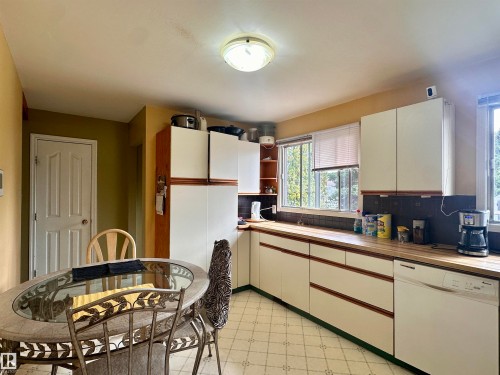 Kitchen featuring an L-shaped counter configuration, white cabinetry with wood-finish accents, and a built-in dishwasher - 10619 108 Avenue, Westlock, AB - Indoor Photo Showing Kitchen